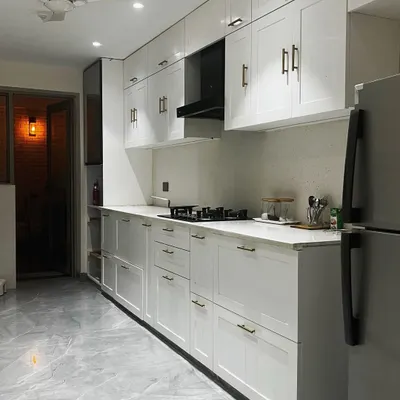 This parallel kitchen in Noida is designed for maximum efficiency. The all-white shaker-style cabinets create a bright and clean look, while the long countertops provide ample workspace.