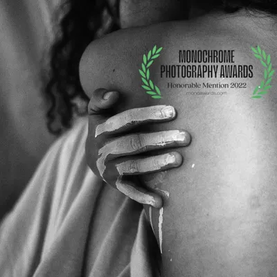 This award-winning monochrome photograph explores touch and texture. The image, which received an honorable mention at the Monochrome Photography Awards, focuses on the detail of a paint-covered hand on skin.