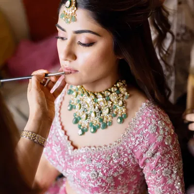 The final touches are just as important as the first. Here, I'm applying lipstick to complete this dreamy pink bridal look, ensuring the shade perfectly complements the outfit and skin tone.