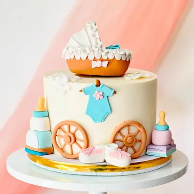 A beautiful baby shower cake with a vintage feel. The design includes a fondant baby carriage, booties, a onesie, and feeding bottles.