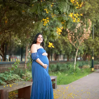 We found the most beautiful spot under the blooming amaltas trees for this outdoor maternity photoshoot. The vibrant blue of her dress against the yellow flowers felt like a celebration of new life.