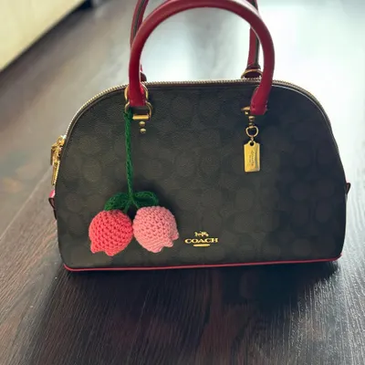 Here’s a look at the handmade tulip bag charm attached to a handbag, showing how it adds a playful and colorful accent.