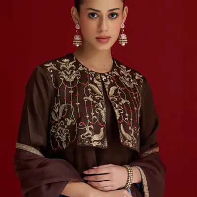 A rich brown suit with a beautifully embroidered jacket. The intricate bird and floral motifs in gold thread add a touch of whimsical elegance to this classic silhouette.