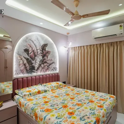 A beautiful bedroom featuring a custom arched headboard with a tropical wallpaper insert and integrated lighting. The pink upholstered bed frame adds a soft, luxurious touch.