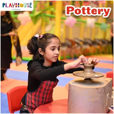 A close-up of a young girl trying her hand at the pottery wheel. Our instructors provide guidance, helping children shape their own clay creations from start to finish.