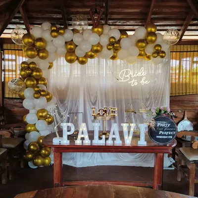 This 'Bride to be' decoration was set up within a rustic wooden gazebo, showing how I can adapt my designs to unique venues. The classic white and gold balloon arch, paired with a neon sign and the bride's name in marquee letters, beautifully complements the warm wood setting.