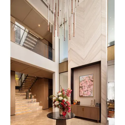 The foyer of the Punjabi Bagh villa showcases our orchestration of volumes. A custom chandelier cascades through the double-height space, drawing the eye upwards and highlighting the chevron-patterned marble and grand staircase.