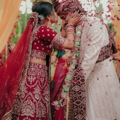 A moment of gentle affection during the wedding ceremony. The bride lovingly touches the groom's face, surrounded by a shower of petals, a candid expression of their bond.