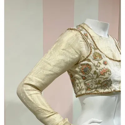 A unique double-layered saree blouse ensemble. It consists of an inner silk jacquard full-sleeve blouse, paired with an intricately embroidered velvet jacket.