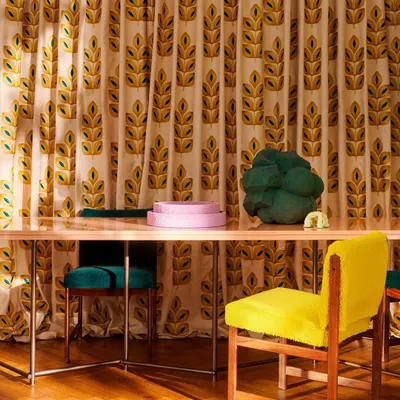 A vibrant dining space where floor-to-ceiling curtains feature a bold, embroidered leaf motif from Élitis. The pop-inspired colors and graphic pattern demonstrate how custom drapery can become a central artistic feature in a room, setting a joyful and energetic tone.