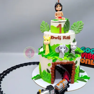 A three-tiered Jungle Book cake for a first birthday, complete with a toy train running through a tunnel in the bottom tier. This cake combines fondant art with interactive elements to create a truly magical experience.