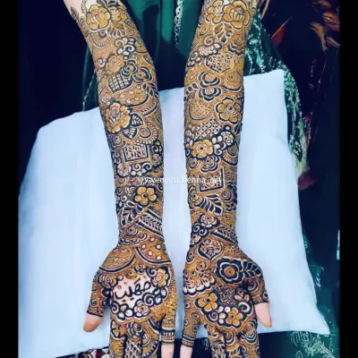 A complete view of the intricate bridal mehndi for Raazia. The design is packed with details, including floral patterns, geometric checks, and the bride's name beautifully written on the palm.