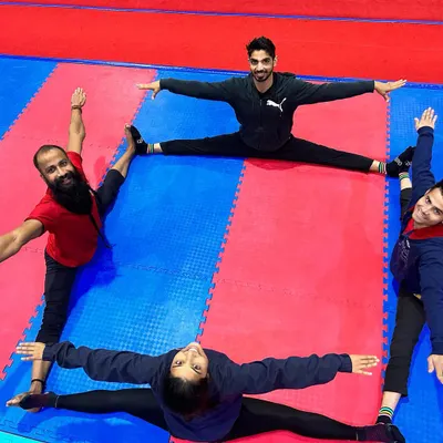 Our students work together on their flexibility. This creative group formation shows four athletes holding a full middle split, a testament to their dedication and our training methods.