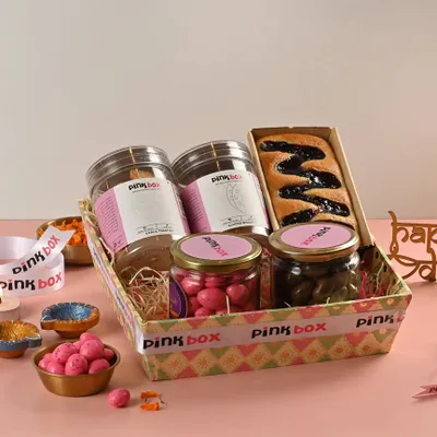 This is our "Gulal" hamper, a vibrant mix of sweet and savory treats. It includes Almond Biscotti, Garlic Toasties, a Blueberry Marble Cake, Pink Almond Dragees, and Chocolate Coated Cashews.