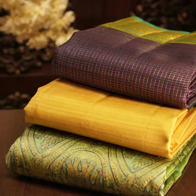 A glimpse of our unique Kanjivaram collection, showcasing a variety of weaves and colors, from checks to paisleys, neatly stacked and ready for you to explore.