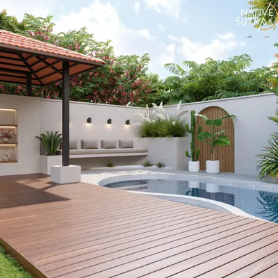 This poolside design features a raised wooden deck leading to a curved pool, complemented by a built-in seating area and a tiled-roof gazebo. We used a mix of pampas grass and cacti to add texture and create a modern, slightly rustic feel.