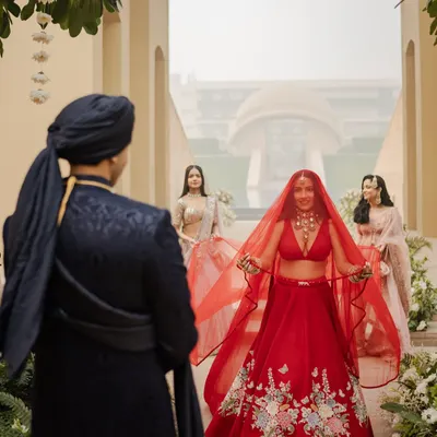 The bride's first look with her groom is always a magical moment. Here, Shubhangi's radiant makeup and classic red lehenga create a breathtaking vision as she walks towards her partner.