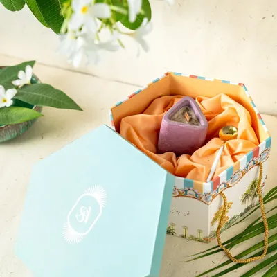 A custom hexagonal gift box designed as part of a wedding invitation suite. The exterior features artwork inspired by the couple's story, and the interior is lined with silk, holding curated gifts for the guests.