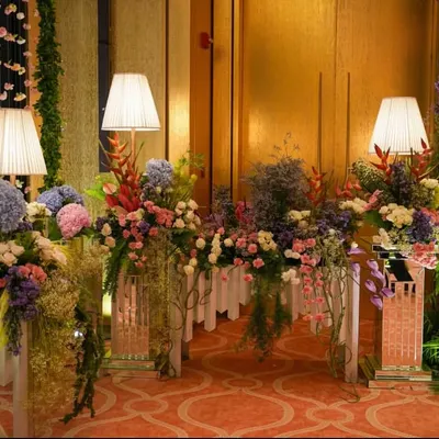 A beautiful pastel-themed setup for a daytime event. The console table is overflowing with a lush arrangement of hydrangeas, roses, and other florals in soft pinks, blues, and purples.