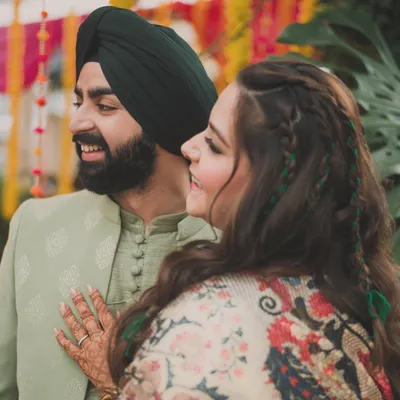 A happy moment between the bride and groom during their mehendi. We chose a handsome pistachio green outfit for him, which contrasted beautifully with her printed kaftan, creating a stylish and coordinated couple look.