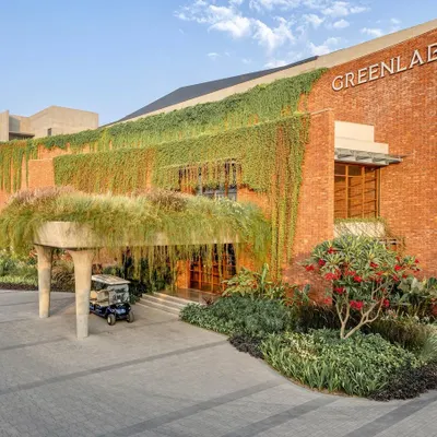 The main entrance to the Greenlab factory, where a canopy of hanging grasses creates a dramatic and natural porte-cochère. This design element immediately establishes the building's connection to the landscape.