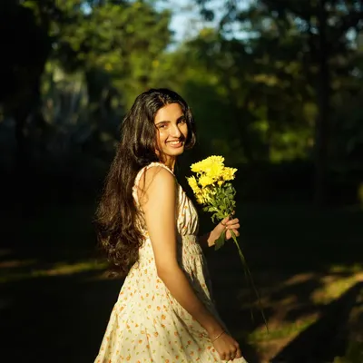 A candid moment of joy in the park. The natural sunlight filtering through the trees creates a beautiful, soft light that feels warm and genuine.