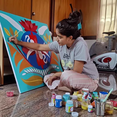 This is where the magic happens. A candid shot of me working on the floor, completely absorbed in painting the details of the custom symmetrical crane artwork, surrounded by my paints.