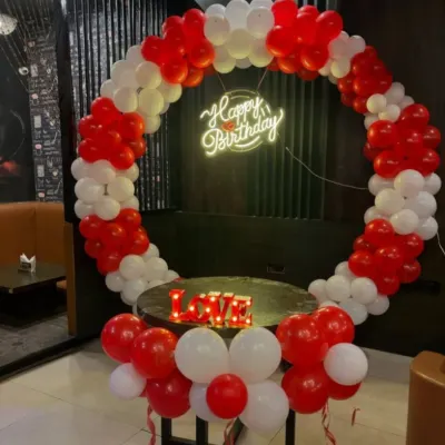 A simple and classic red and white balloon ring, perfect for smaller spaces or as an addition to a larger decor scheme. The setup includes a neon sign and a "LOVE" marquee, ideal for an intimate anniversary or Valentine's celebration.