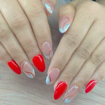 A sophisticated and artistic design. This set combines bold, glossy red nails with accent nails featuring abstract, free-flowing swirls of red and light blue on a nude base.