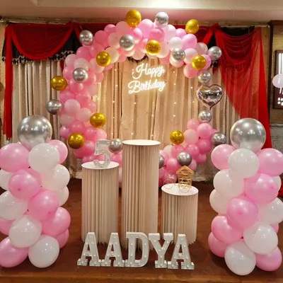 A beautiful pink, white, and silver balloon arch with a neon 'Happy Birthday' sign. This classic setup is perfect for a sweet and stylish celebration.