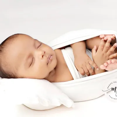 A newborn rests in a 'potato sack' pose in a pure white setup. This minimalist approach creates a timeless, angelic portrait.
