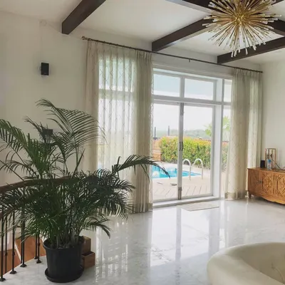 The main living area of this Mysore residence is defined by its direct connection to the rooftop pool. The open-plan layout, high ceilings with wooden beams, and large glass doors make the space feel expansive and full of light.
