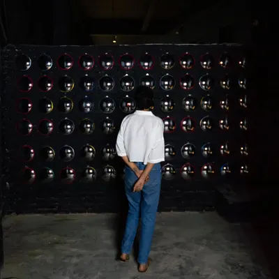 A viewer interacting with the 'Surfing' installation. The wall of mirrors creates an engaging and thought-provoking experience, making the observer a part of the artwork itself.