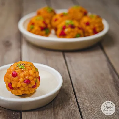 A perfect, single Jodhpuri Laddoo, also known as Boondi Laddoo. It's studded with colourful boondi and nuts, making it as beautiful as it is delicious.