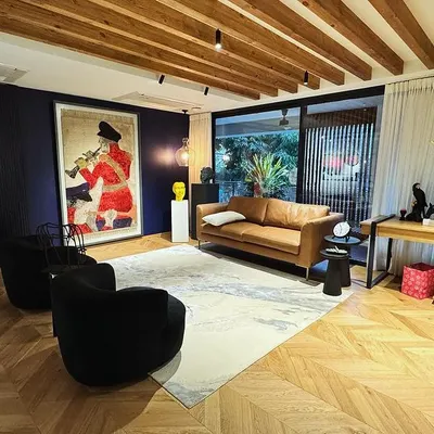 This open-plan study is designed to be warm and inviting. We built a long wooden desk and shelving unit that spans the wall, set against a deep blue accent wall and herringbone wood floors.