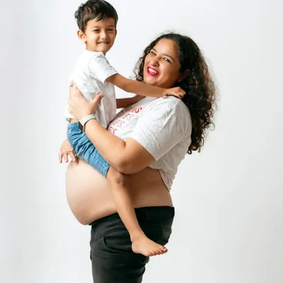 A joyful moment between a mom and her son. Including older siblings in the maternity shoot is a wonderful way to make them feel special and excited.