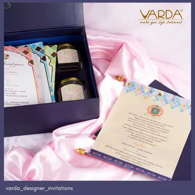 A custom wedding invitation suite in a deep blue box. This design features cards with a modern mosaic pattern, paired with jars of gourmet treats for a complete gifting experience.