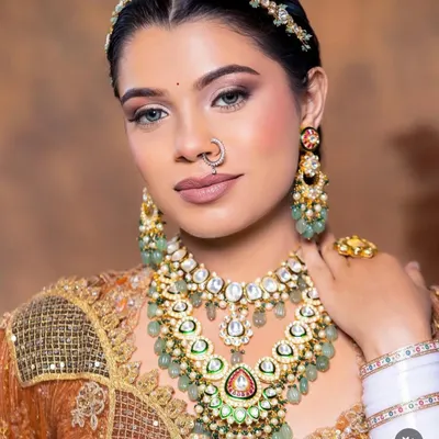 A close-up of this stunning bridal look. The layered Kundan necklace with green beadwork, matching matha patti, and nath creates a breathtakingly beautiful effect.