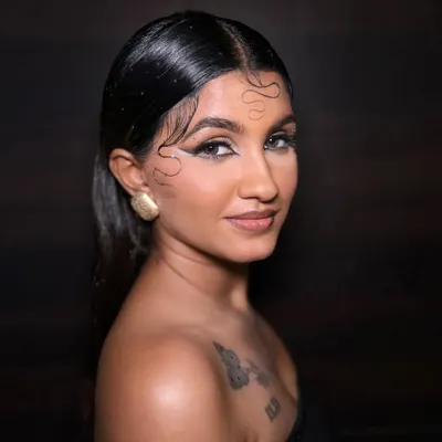 This editorial look combines a wet-look hairstyle with a bold, abstract graphic eyeliner. The skin is kept fresh and glowing to balance the strong eye, creating a modern and high-fashion statement.