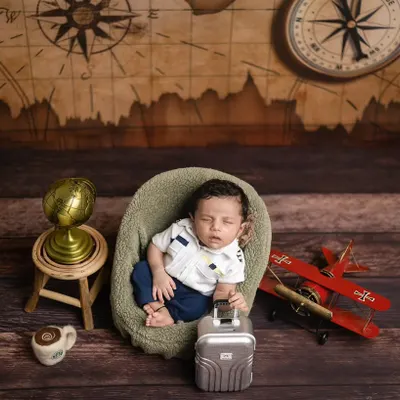 Ready for takeoff! This little pilot is all set for his first adventure, surrounded by a vintage map, a toy plane, and a globe. It’s a perfect theme for travel-loving families.