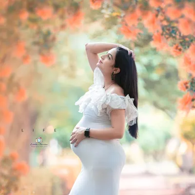 The soft, diffused light of a garden setting is perfect for creating ethereal maternity portraits. This image captures a moment of quiet reflection amidst the beauty of nature.