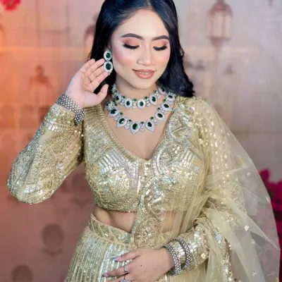 A beautiful soft glam look for an engagement ceremony. The focus is on flawless skin, gentle contouring, and shimmery eyes that complement the golden lehenga and emerald jewelry.