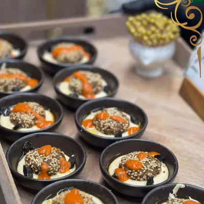 Falafel, but with a gourmet twist. I serve my sesame crusted falafel in individual bowls on a bed of creamy hummus, topped with a flavorful red pepper sauce.