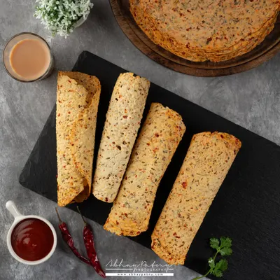 This flat lay of khakhra or papad is styled with chai and chutney, presenting it as a perfect tea-time snack. The composition is clean and balanced.
