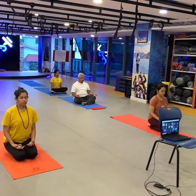 A hybrid yoga session in action, with some participants joining in person and others connecting remotely via a live video stream. This flexible model ensures that no team member misses out, regardless of their location.