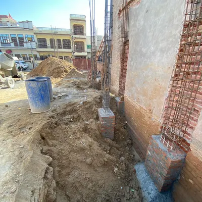 The start of a new builder floor project in Delhi. This image shows the excavation and the placement of rebar for the foundation columns, the critical first step.