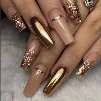 Make a bold statement with these dramatic coffin-shaped nail extensions. The design combines reflective gold chrome, nude polish, and sparkling gold glitter for a truly glamorous effect.