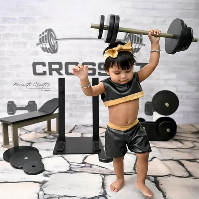 Future weightlifting champion! This little girl shows off her strength in our super fun and unique CrossFit gym setup. These themed shoots are a great way to showcase your baby's energetic personality.