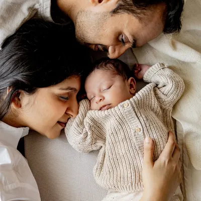 A quiet moment with mum and dad. This overhead shot of a newborn sleeping peacefully in their parents' arms shows the beautiful, protective bubble of love that surrounds a new baby. I love capturing these serene moments during in-home newborn sessions.