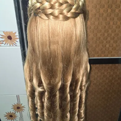 A clear view of the signature braided crown hairstyle. This demonstrates how the thick braid wraps around the head, creating a beautiful, structured look from the front, while the back is left open with curls.